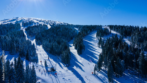 Aerial view at the slope on ski resort. Forest and ski slope from air. Winter landscape from a drone.