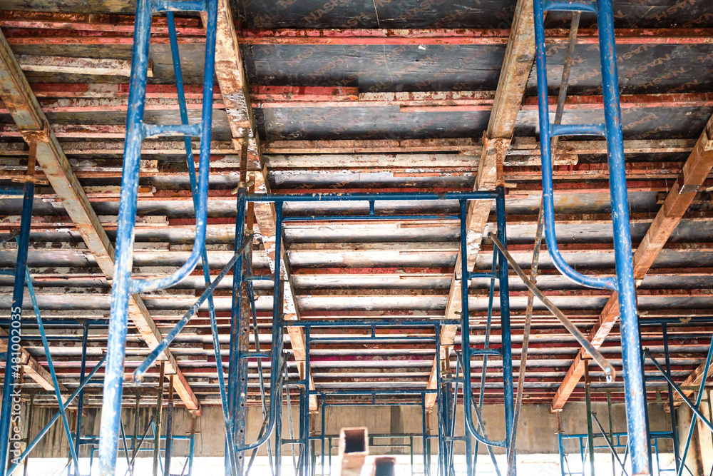 Setting up steel scaffolding to support floors for concrete work on tall buildings. A view up under the floor to support the concrete floor. Setting up a concrete pouring form on the second floor.