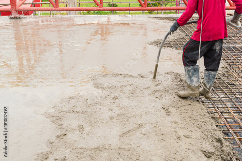Construction workers stir the cement with a hose on the floor of the building where fresh concrete is poured. Concrete pouring work. Adjusting the concrete to be consistent is necessary to do.