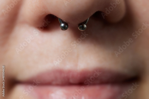 Closeup of a young woman's visage with piercing septum hanging from her nose.