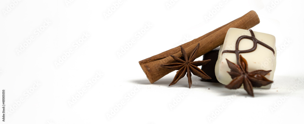 Chocolate candies, cinnamon and cloves on a white background.