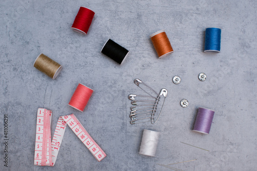Composition with threads and sewing accessories on a gray background