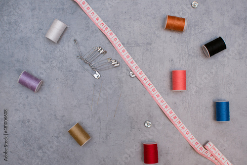 Composition with threads and sewing accessories on a gray background