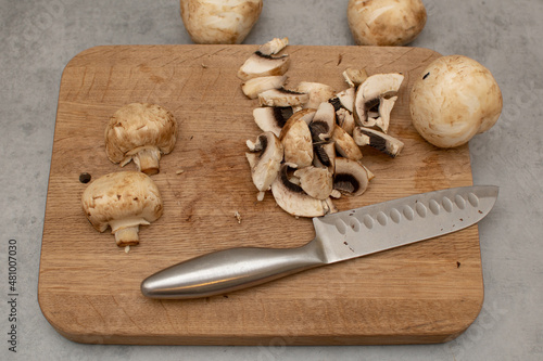 Raw delicious fresh white champignon on a wooden chopping board. Vegetarian recipe. Ingredients for cooking. Sliced portobello mushrooms on a light background.