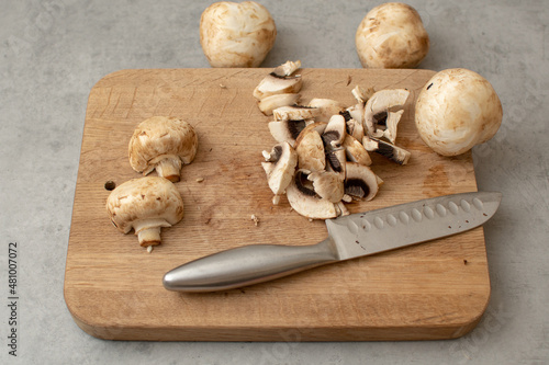 Raw delicious fresh white champignon on a wooden chopping board. Vegetarian recipe. Ingredients for cooking. Sliced portobello mushrooms on a light background.