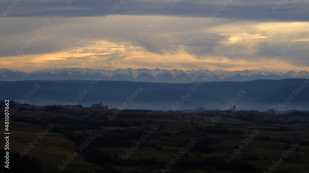 Carpathian mountains over the foggy field in Transylvania at dusk