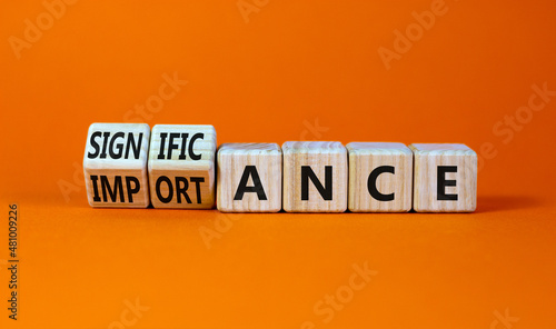 Significance and importance symbol. Turned wooden cubes and changed the word importance to significance. Beautiful orange background, copy space. Business, significance and importance concept.