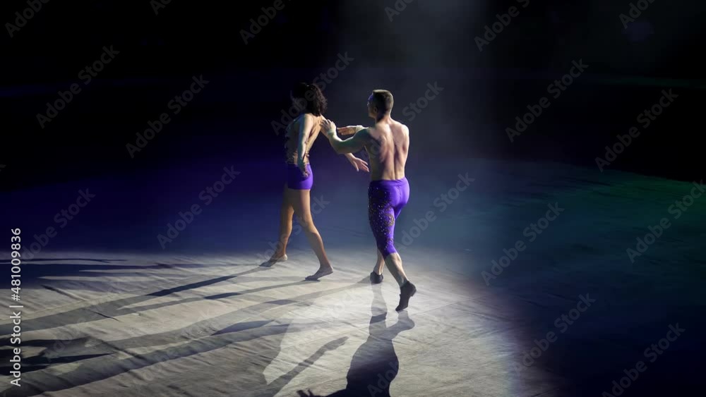 A duo of gymnasts arrange acrobatic performances. Circus artists create shows for the audience. Flexible, athletic, gymnasts. romantic show. Contour light. An acrobat balances in an acrobatic pose A duo of gymnasts arrange acrobatic performances. Circus artists create shows for the audience. Flexible, athletic, gymnasts. romantic show. Contour light. An acrobat balances in an acrobatic pose