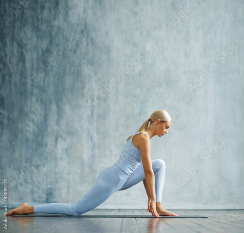 Young slender blonde woman in sportswear is engaged in fitness in a spacious training room. Sport, health, gymnastics and lifestyle concept.