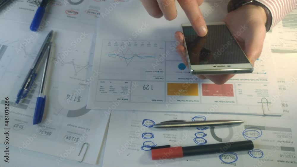 Auditor counts financials from charts on his smartphone calculator top view 4k Auditor counts financials from charts on his smartphone calculator top view 4k