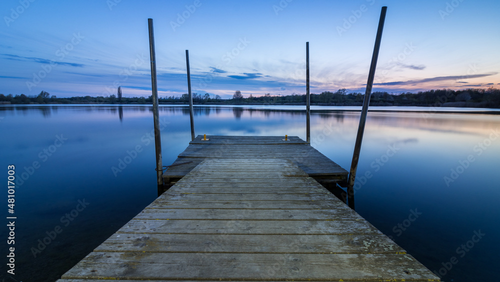 Jetty runs straight into the water after sunset at the lake