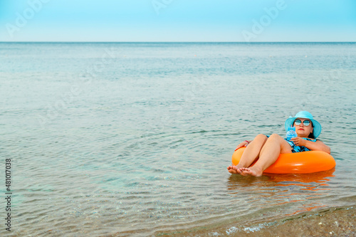 Woman in a straw hat and glasses in the sea in a swimming circle.