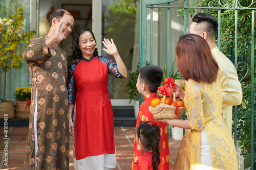 Happy grandparents greeting their children and grandchildren who came for Lunar New Year celebration at house entrance