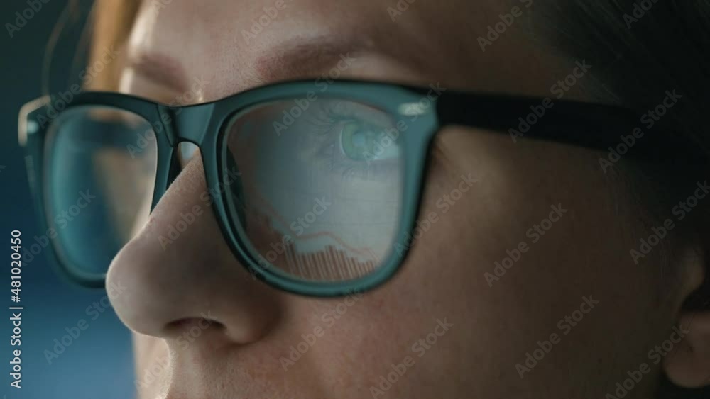 Woman in glasses looking on the monitor and and working with charts and analytics. The monitor screen is reflected in the glasses. Work at night. Extreme close-up Woman in glasses looking on the monitor and and working with charts and analytics. The monitor screen is reflected in the glasses. Work at night. Extreme close-up