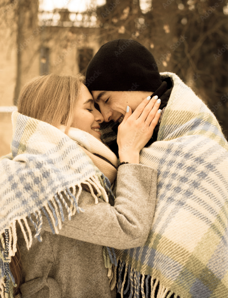 Loving couple in a blanket in winter. The guy hugs a girl on the street in winter.