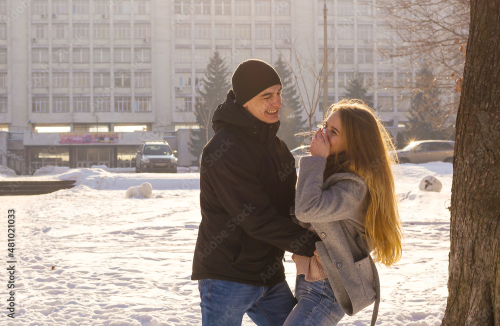 A guy and a girl are indulge and laugh in the winter park