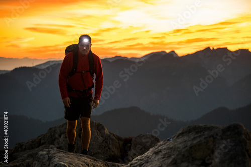 Man uses headlamp to navigate while hiking in the mountains. photo