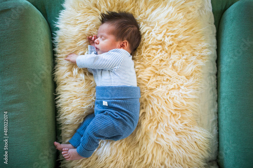 High angle view of newborn baby lying on sheepskin blanket.