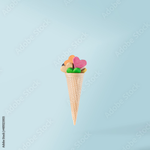 Colorful hearts with ice cream cone on light blue pastel background. Creative love idea. Contemporary style.