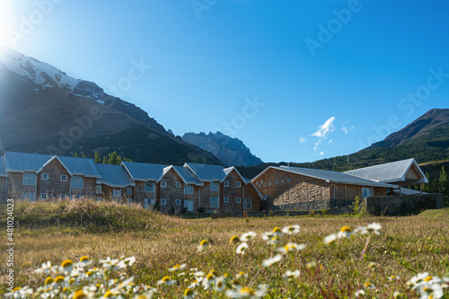 Refugio en un día soleado con montañas de fondo desenfocadas y flores en el cuadro en la zona de Torres del Paine. Patagonia Chilena 