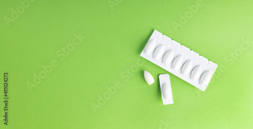 Anal or vaginal candles on a green background with copy space photo