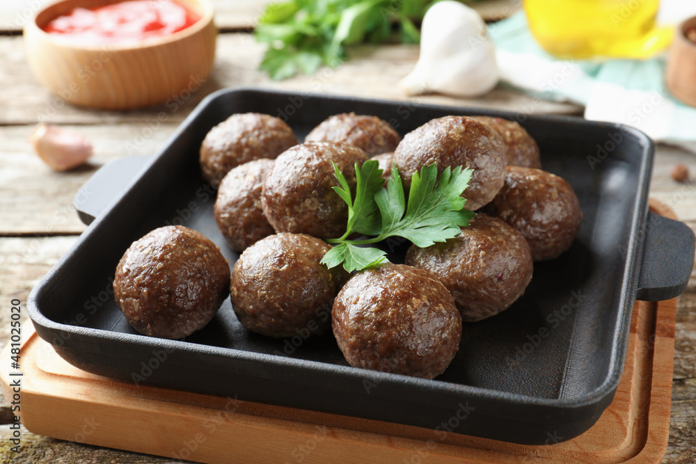 Tasty cooked meatballs with parsley on wooden table, closeup