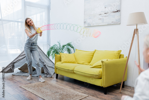 Smiling woman playing with slinky and child in living room. photo