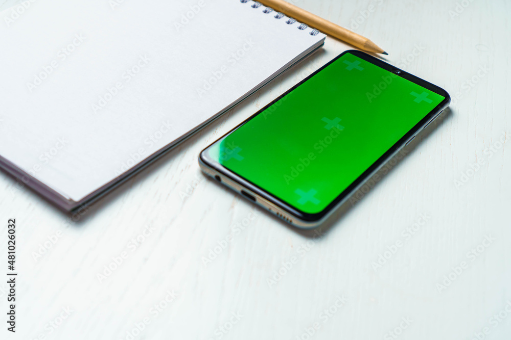 White blank notepad smartphone green screen mockup and pencil flat lay. Tamplate for design White blank notepad smartphone green screen mockup and pencil flat lay. Tamplate for design