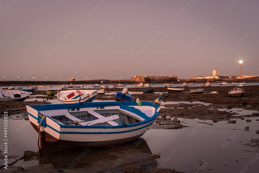 Boats docked in La Caleta beach at low tide at sunrise, Cadiz, Andalusia, Spain