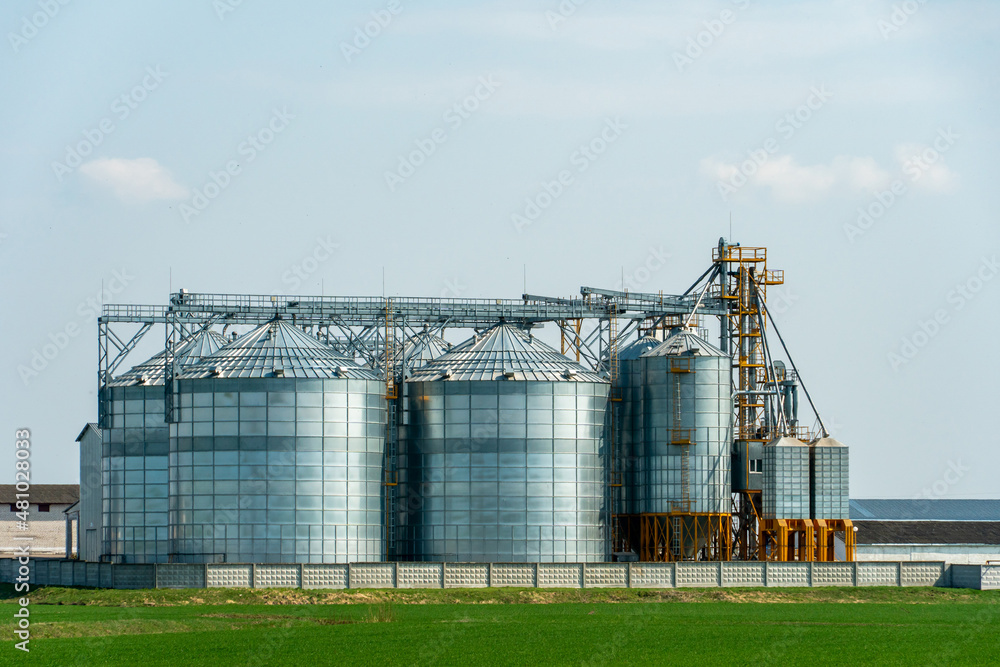 A large modern plant for the storage and processing of grain crops. view of the granary on a sunny day against the blue sky. End of harvest season. A large modern plant for the storage and processing of grain crops. view of the granary on a sunny day against the blue sky. End of harvest season.