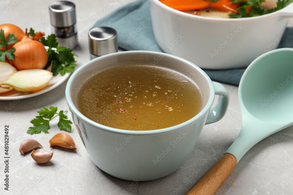 Hot delicious bouillon in cup on light grey table Hot delicious bouillon in cup on light grey table