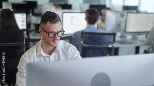 Professional Creative Businessman Working on Decktop Computer in Open Space Office . Male Professional Typing on PC Keyboard at Office Workplace. Portrait of Positive Business Man Looking at Computer photo