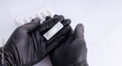 Hands in black gloves  opens suppositories for anal or vaginal use. Medical candles for the treatment of vaginitis, erosion, cystitis, Candida, vulvovaginitis, endometritis, thrush and inflammation.  photo