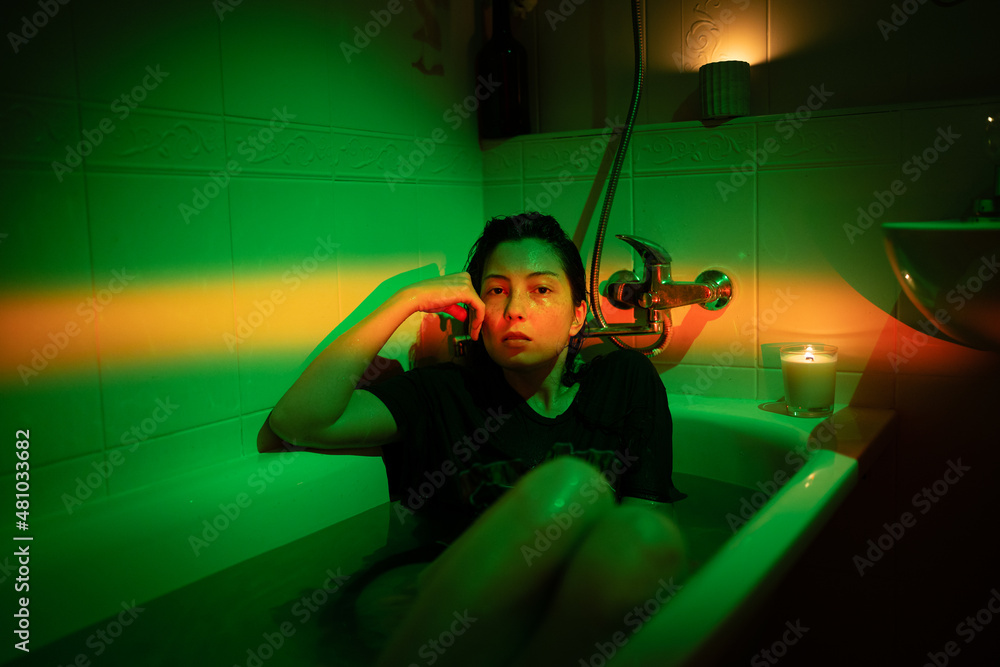 Portrait of unhappy woman taking bath dressed and tired. Drunk young