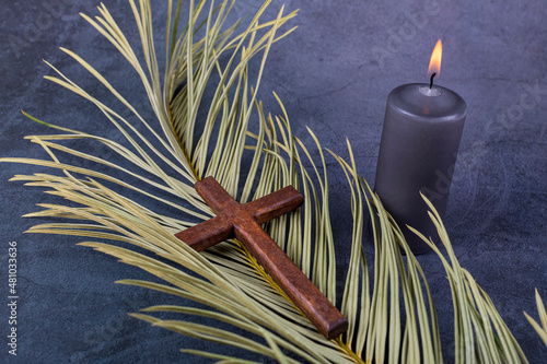 Catholic Cross with palm leaf and burning candle. Ash Wednesday, Lent season, Holy Week, Good Friday and Palm Sunday concept. Copy space. photo