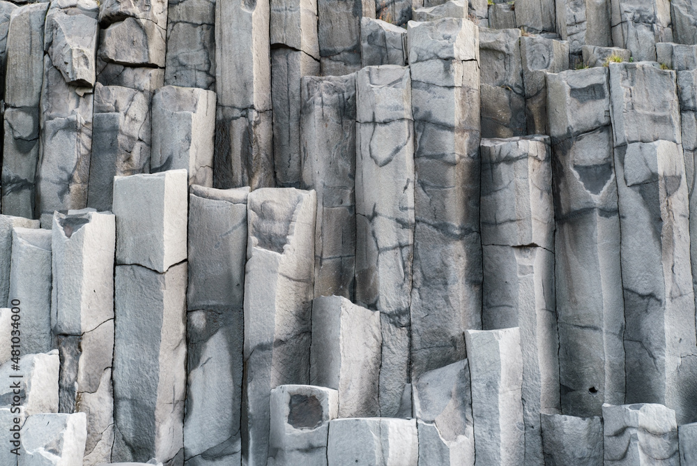Basalt rock pillars columns at Reynisfjara beach near Vik, South Iceland. Unique geological volcanic formations. Natural stone texture background.