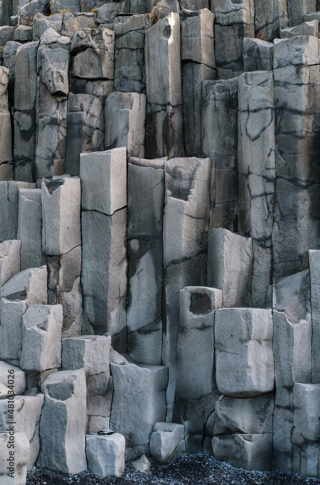 Basalt rock pillars columns at Reynisfjara beach near Vik, South Iceland. Unique geological volcanic formations. Natural stone texture background.