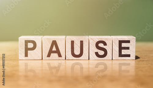 Photos Wooden Blocks with the text: Pause on a green-brown background