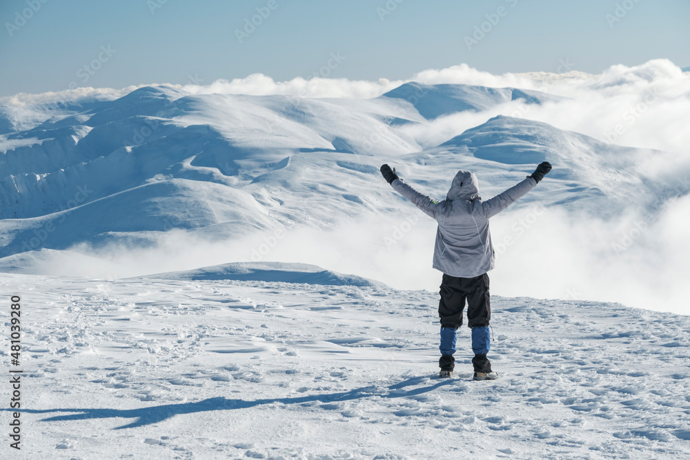 a man staying with hands up and look to clouds in mountains valley