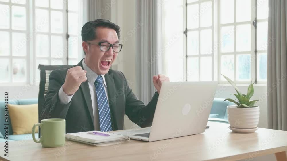 Asian Businessman With Glasses Wearing Business Suit Looking At Computer Screen And Being Happy After Winning The Project Bid While Working At Home.
Asian Businessman With Glasses Wearing Business Suit Looking At Computer Screen And Being Happy After Winning The Project Bid While Working At Home.