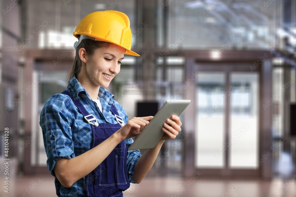 Young woman architect wearing hardhat at construction site while working. Young woman architect wearing hardhat at construction site while working.