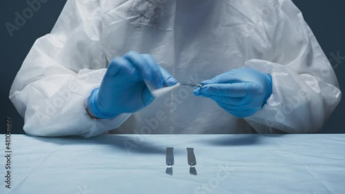 close-up of the doctor's hands at the table in a bathrobe and gloves working with surgical instruments