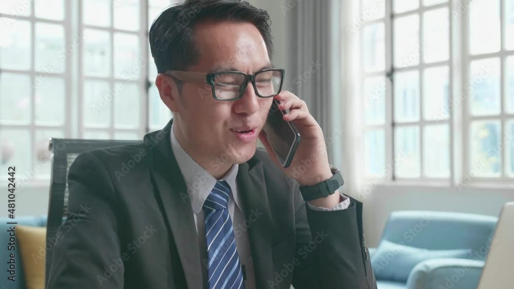 Asian Businessman With Glasses Wearing Business Suit Answering The Phone Call While Using The Computer For Working At Home.
Asian Businessman With Glasses Wearing Business Suit Answering The Phone Call While Using The Computer For Working At Home.