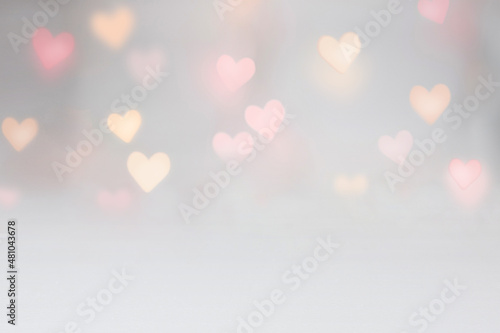 Valentine background mockup with pink and yellow heart shaped light bokeh on a grey seamless backdrop. Use for digital product mockup placement or as a background for text. photo