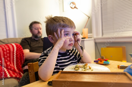 фотографія Adorable Young Boy Watches Television While Eating Home-Cooked Dinner