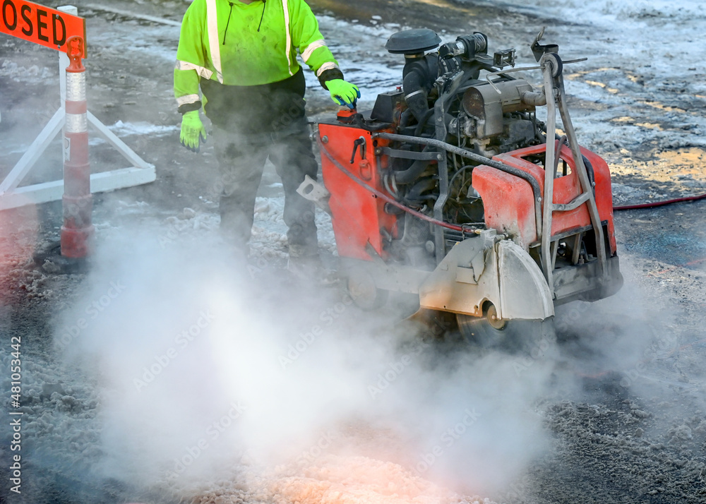Worker using an asphalt saw cutting machine being used to excavate street