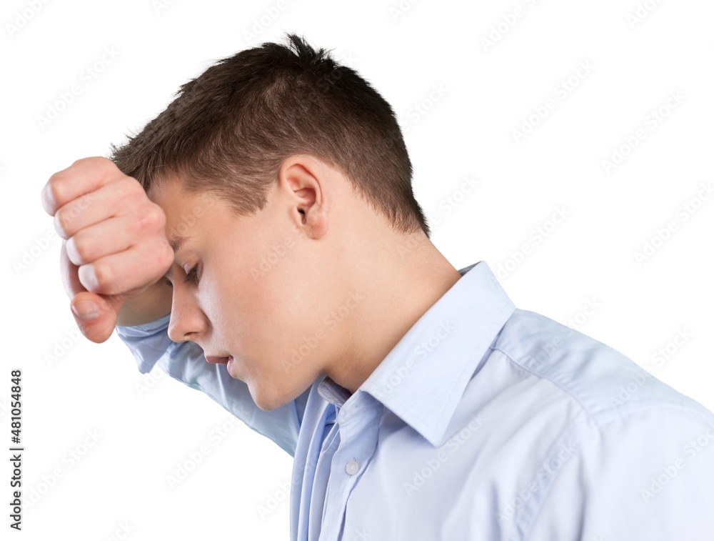 Depressed young man with fist clenched leaning his head against a wall Depressed young man with fist clenched leaning his head against a wall