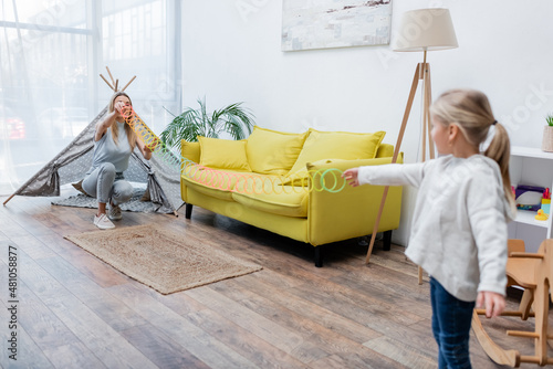 Blurred kid playing with slinky and mom at home.