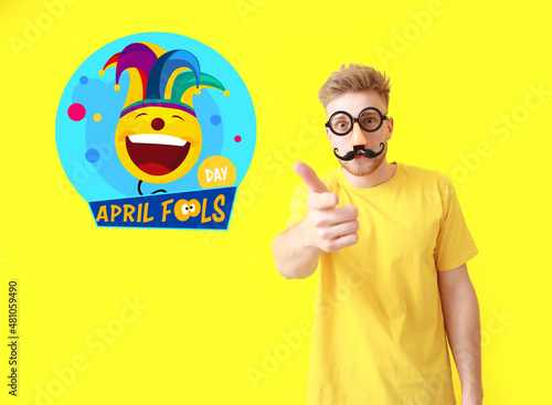 Funny man with party decor for April Fools' Day on color background