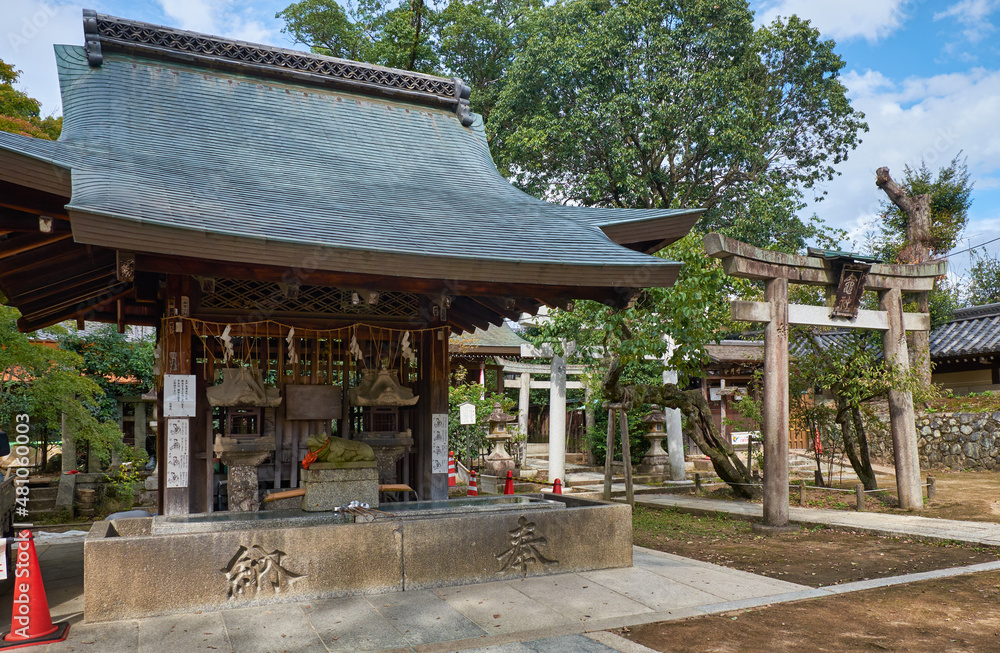 Naklejka premium The water ablution pavilion with the stone torii gate at Kitano Tenmangu shrine. Kyoto. Japan